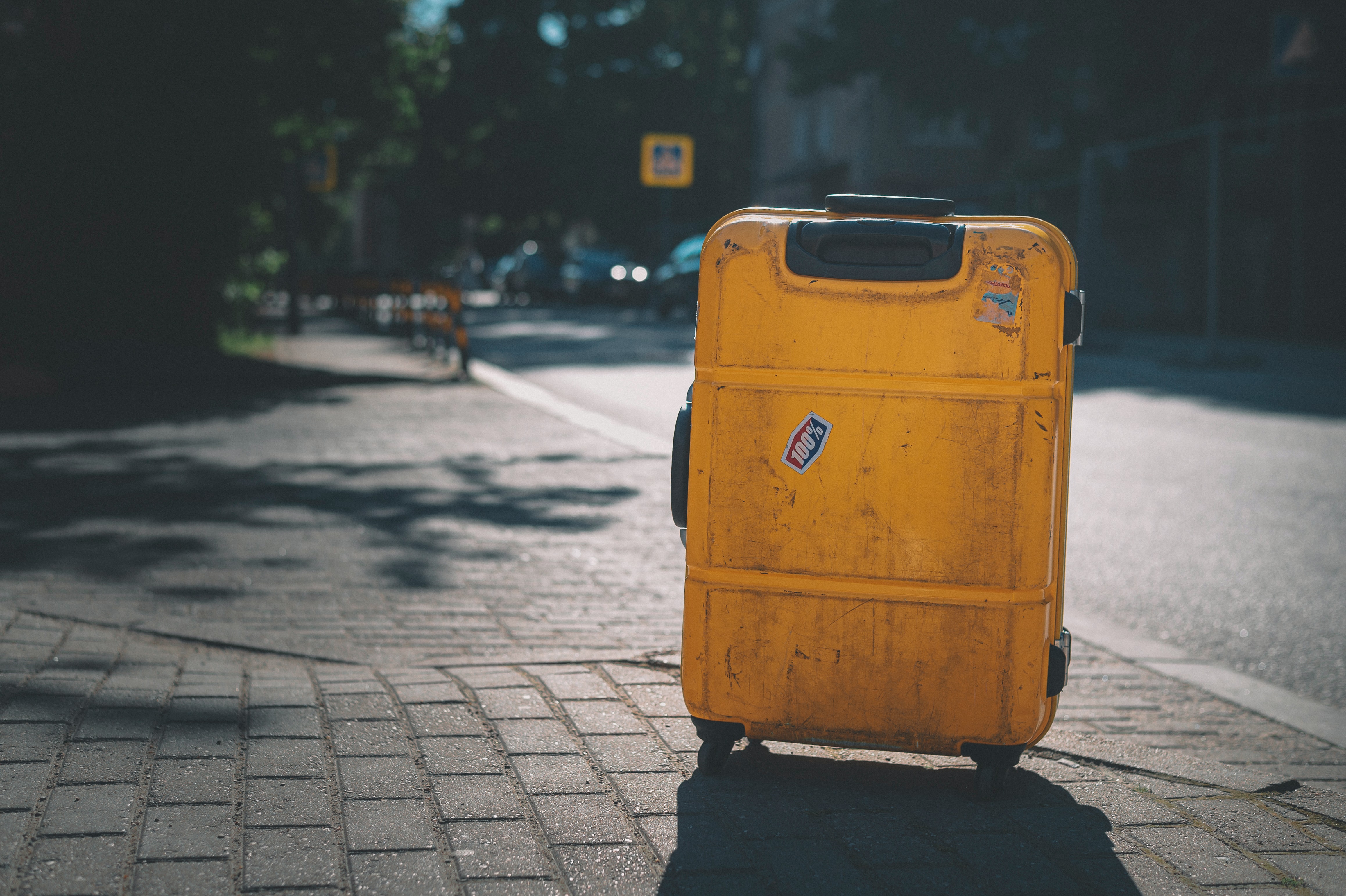 yellow suitcase on a rainy sidewalk