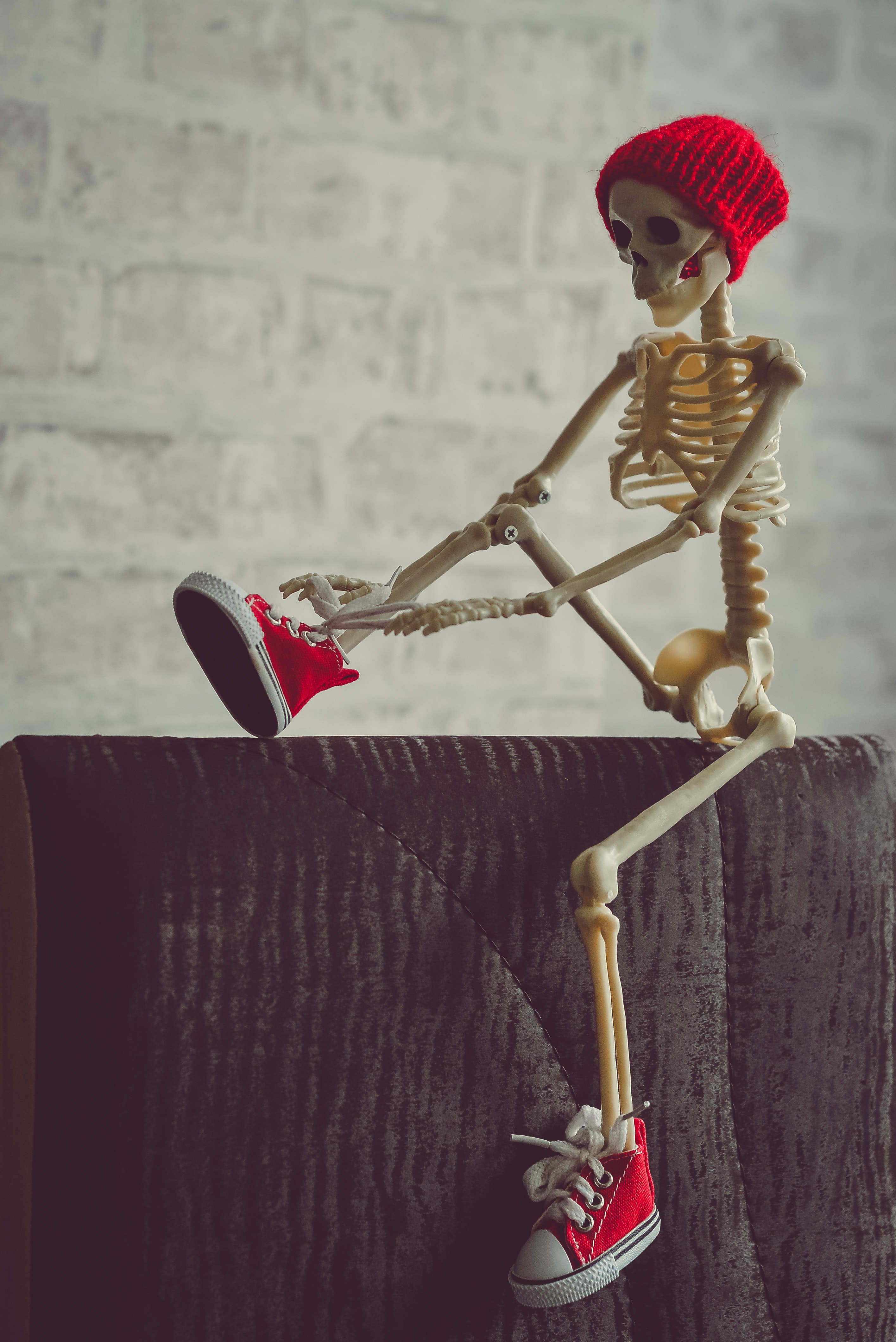 a small skeleton wearing a red beanie and red converse